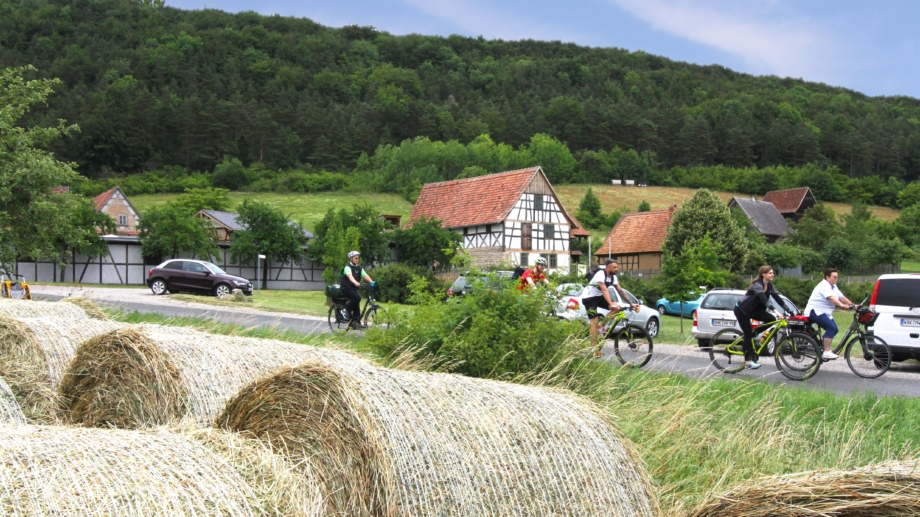 Quelle: Landratsamt Weimarer Land, Foto: Uwe Germar Radfahrer vor dem Thüringer Freilichtmuseum Hohenfelden mit Strohballen im Vordergrund